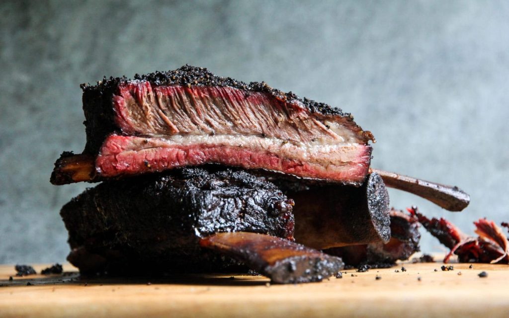 Smoked beef ribs with dark bark and visible smoke ring